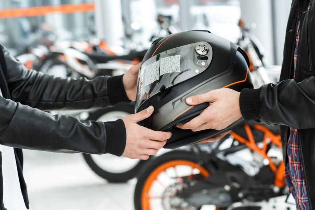 image of two people exchanging helmets - what to look for when buying a helmet with Motohorse