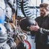 image of a man holding a motorcycle helmet in a bike shop - learn how much you should pay for a good motorcycle helmet with Motohorse, a motorcycle & powersports parts and accessories shop