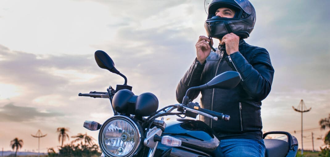 image of man on a motorcycle taking off helmet - motorcycle helmet size with motohorse, a motorcycle & powersports parts and accessories shop